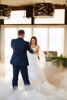 the first dance of the bride and groom inside a restaurant with heavy smoke