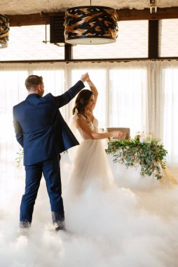 the first dance of the bride and groom inside a restaurant with heavy smoke