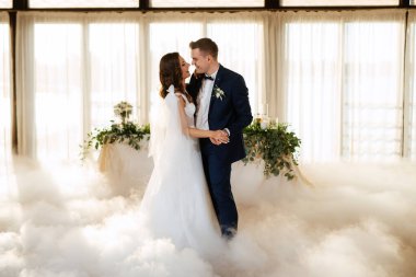 the first dance of the bride and groom inside a restaurant with heavy smoke