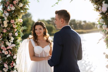 wedding ceremony on a high pier near the river with invited guests