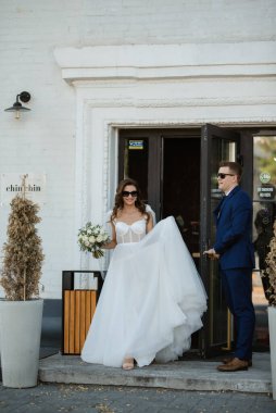 Gelin ve damat bir kokteyl barının içinde. Parlak bir atmosferde, bir bardak içkiyle.