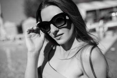 Hasır şapkalı ve pembe mayosu olan bir kız şehir havuzunda güneşleniyor.