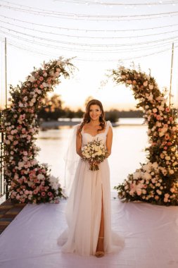 bride against the background of a yellow sunset on a pier near the river