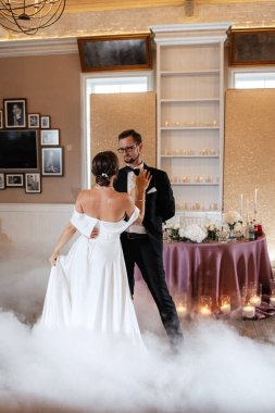 the first dance of the bride and groom inside a restaurant with heavy smoke