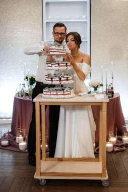 newlyweds happily cut, laugh and taste the wedding cake