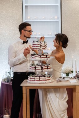 newlyweds happily cut, laugh and taste the wedding cake