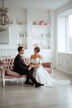 Siyah takım elbiseli damat papyonlu ve parlak bir stüdyoda dar beyaz elbiseli gelin.