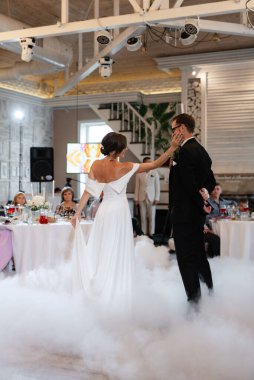 the first dance of the bride and groom inside a restaurant with heavy smoke
