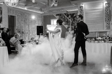 the first dance of the bride and groom inside a restaurant with heavy smoke