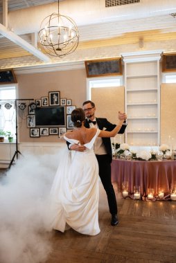 the first dance of the bride and groom inside a restaurant with heavy smoke