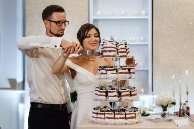 newlyweds happily cut, laugh and taste the wedding cake