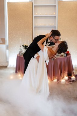 the first dance of the bride and groom inside a restaurant with heavy smoke