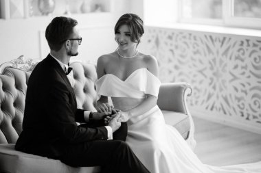 Siyah takım elbiseli damat papyonlu ve parlak bir stüdyoda dar beyaz elbiseli gelin.