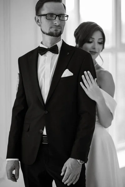 stock image groom in a black suit with a bow tie and the bride in a tight white dress in a bright studio