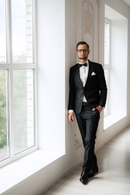 Parlak bir stüdyoda papyonlu siyah takım elbiseli bir damat.