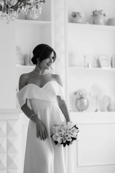 ブルネット花嫁でタイトウェディングドレスで明るいスタジオで花束 — ストック写真