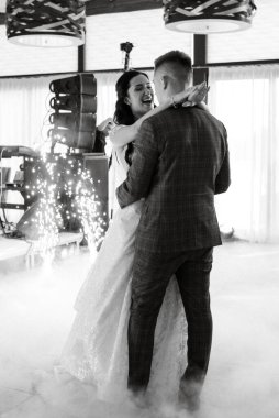 the first dance of the bride and groom inside a restaurant with heavy smoke