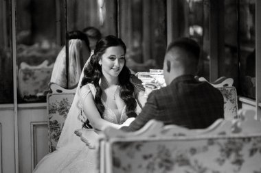 Gelin ve damat bir kokteyl barının içinde. Parlak bir atmosferde, bir bardak içkiyle.