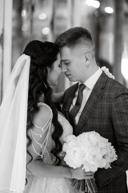 Gelin ve damat bir kokteyl barının içinde. Parlak bir atmosferde, bir bardak içkiyle.