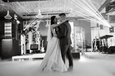 the first dance of the bride and groom inside a restaurant with heavy smoke