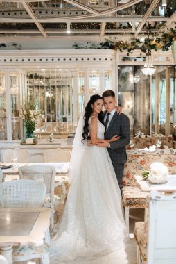 Gelin ve damat bir kokteyl barının içinde. Parlak bir atmosferde, bir bardak içkiyle.