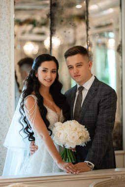 Gelin ve damat bir kokteyl barının içinde. Parlak bir atmosferde, bir bardak içkiyle.