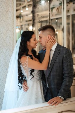 Gelin ve damat bir kokteyl barının içinde. Parlak bir atmosferde, bir bardak içkiyle.