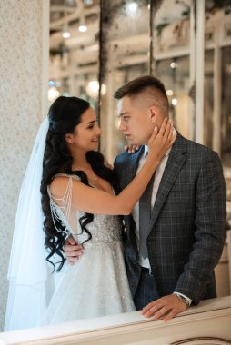 Gelin ve damat bir kokteyl barının içinde. Parlak bir atmosferde, bir bardak içkiyle.