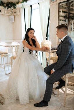 Gelin ve damat bir kokteyl barının içinde. Parlak bir atmosferde, bir bardak içkiyle.