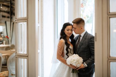 Gelin ve damat bir kokteyl barının içinde. Parlak bir atmosferde, bir bardak içkiyle.