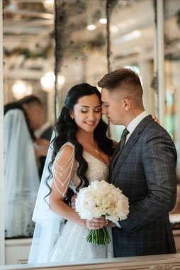 Gelin ve damat bir kokteyl barının içinde. Parlak bir atmosferde, bir bardak içkiyle.