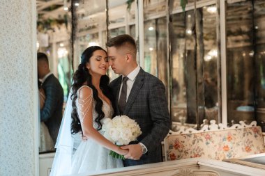 Gelin ve damat bir kokteyl barının içinde. Parlak bir atmosferde, bir bardak içkiyle.