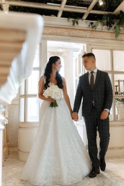 Gelin ve damat bir kokteyl barının içinde. Parlak bir atmosferde, bir bardak içkiyle.