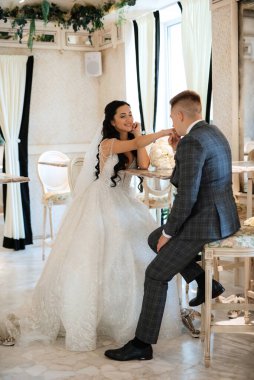 Gelin ve damat bir kokteyl barının içinde. Parlak bir atmosferde, bir bardak içkiyle.