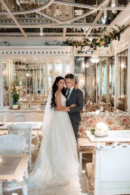 Gelin ve damat bir kokteyl barının içinde. Parlak bir atmosferde, bir bardak içkiyle.