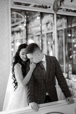 Gelin ve damat bir kokteyl barının içinde. Parlak bir atmosferde, bir bardak içkiyle.