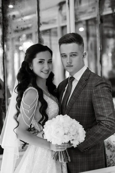 Gelin ve damat bir kokteyl barının içinde. Parlak bir atmosferde, bir bardak içkiyle.