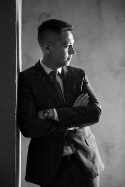 Gri ekose takım elbiseli bir damadın portresi. Düğün günü bir barda kravat takmış.