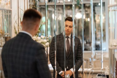 Gri ekose takım elbiseli bir damadın portresi ve aynalı bir kravat.