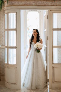 Parlak bir kafede aynalı beyaz elbiseli bir gelinin portresi.