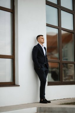 Koyu renk yün takım elbiseli bir damadın portresi.