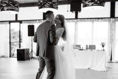 the first wedding dance of the bride and groom inside the restaurant hall in sunset light