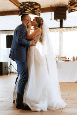 the first wedding dance of the bride and groom inside the restaurant hall in sunset light