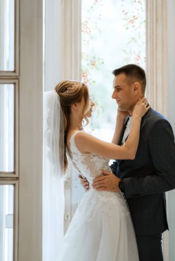 Gelin ve damat bir kokteyl barının içinde. Parlak bir atmosferde, bir bardak içkiyle.