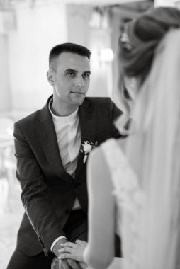 Gelin ve damat bir kokteyl barının içinde. Parlak bir atmosferde, bir bardak içkiyle.