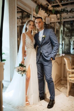 Gelin ve damat bir kokteyl barının içinde. Parlak bir atmosferde, bir bardak içkiyle.