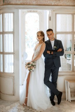 Gelin ve damat bir kokteyl barının içinde. Parlak bir atmosferde, bir bardak içkiyle.