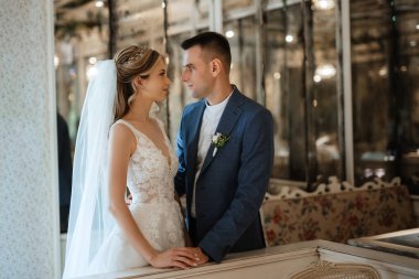 Gelin ve damat bir kokteyl barının içinde. Parlak bir atmosferde, bir bardak içkiyle.