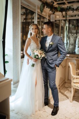 Gelin ve damat bir kokteyl barının içinde. Parlak bir atmosferde, bir bardak içkiyle.