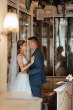 Gelin ve damat bir kokteyl barının içinde. Parlak bir atmosferde, bir bardak içkiyle.